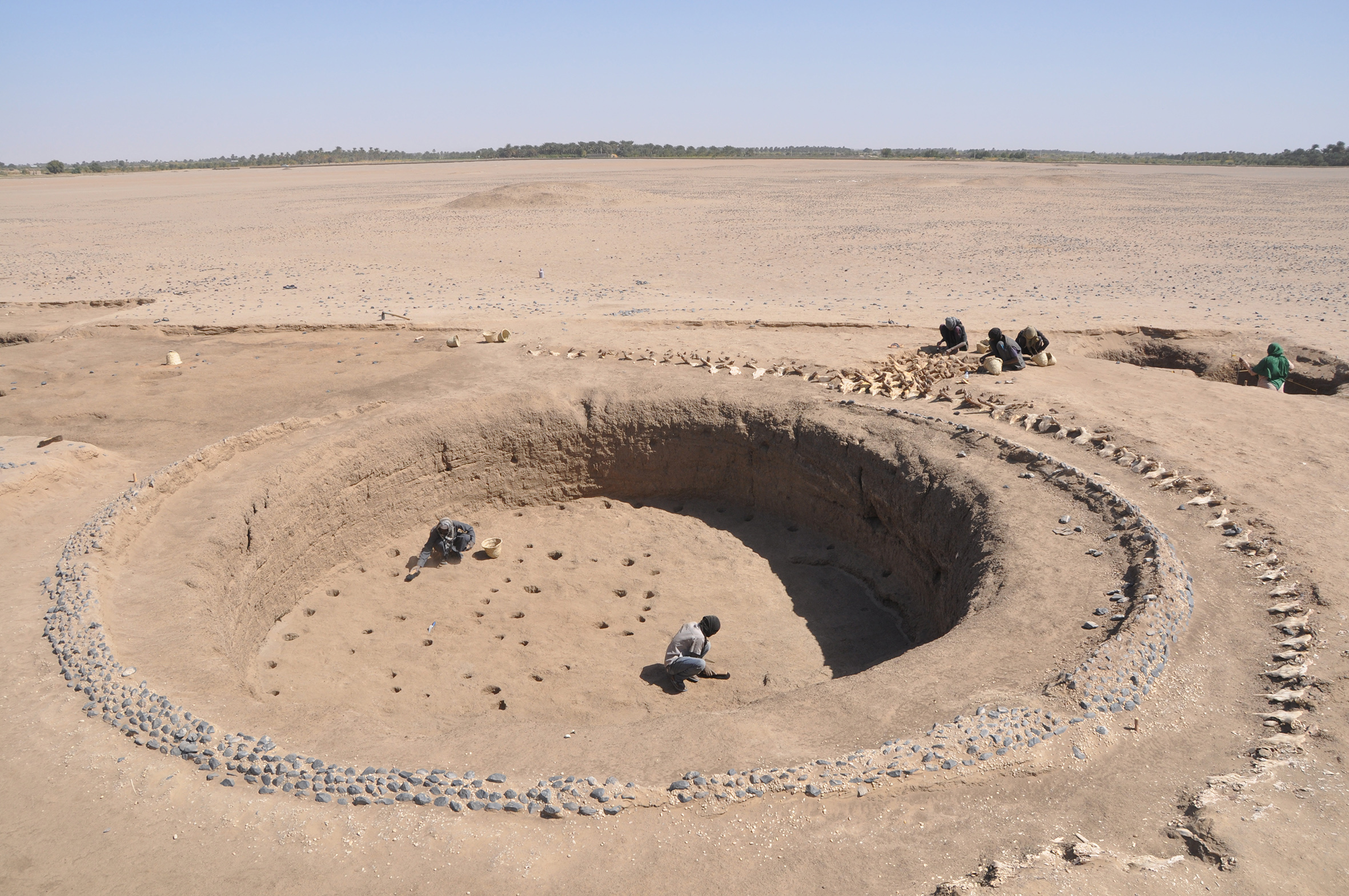 View of the first Kerma royal tomb (Kerma moyen I, 2050-1950 BC). One can see the edge of the burial tumulus made of earth and stones, the post holes of a wooden architectural structure inside the burial pit and more than 1400 bucrania to the south of the tomb. The diameter of the burial pit is about 10 metres.
